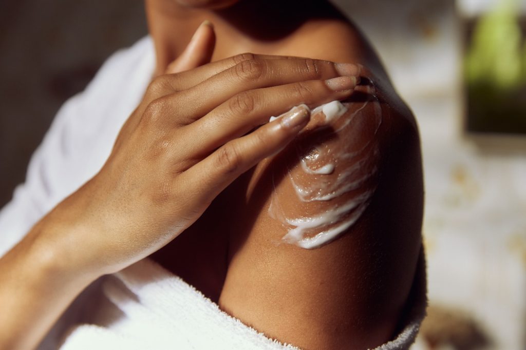 Mulher hidrata a pele com hidratante natural