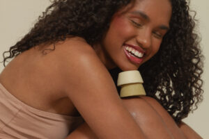 Mulher negra com cabelo natural sorrindo com xampu e condicionador em barra