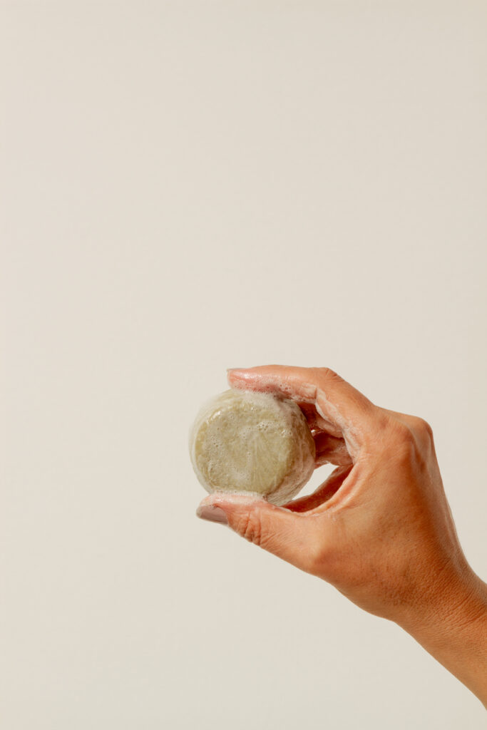 fotografia de uma mão segurando xampu em barra